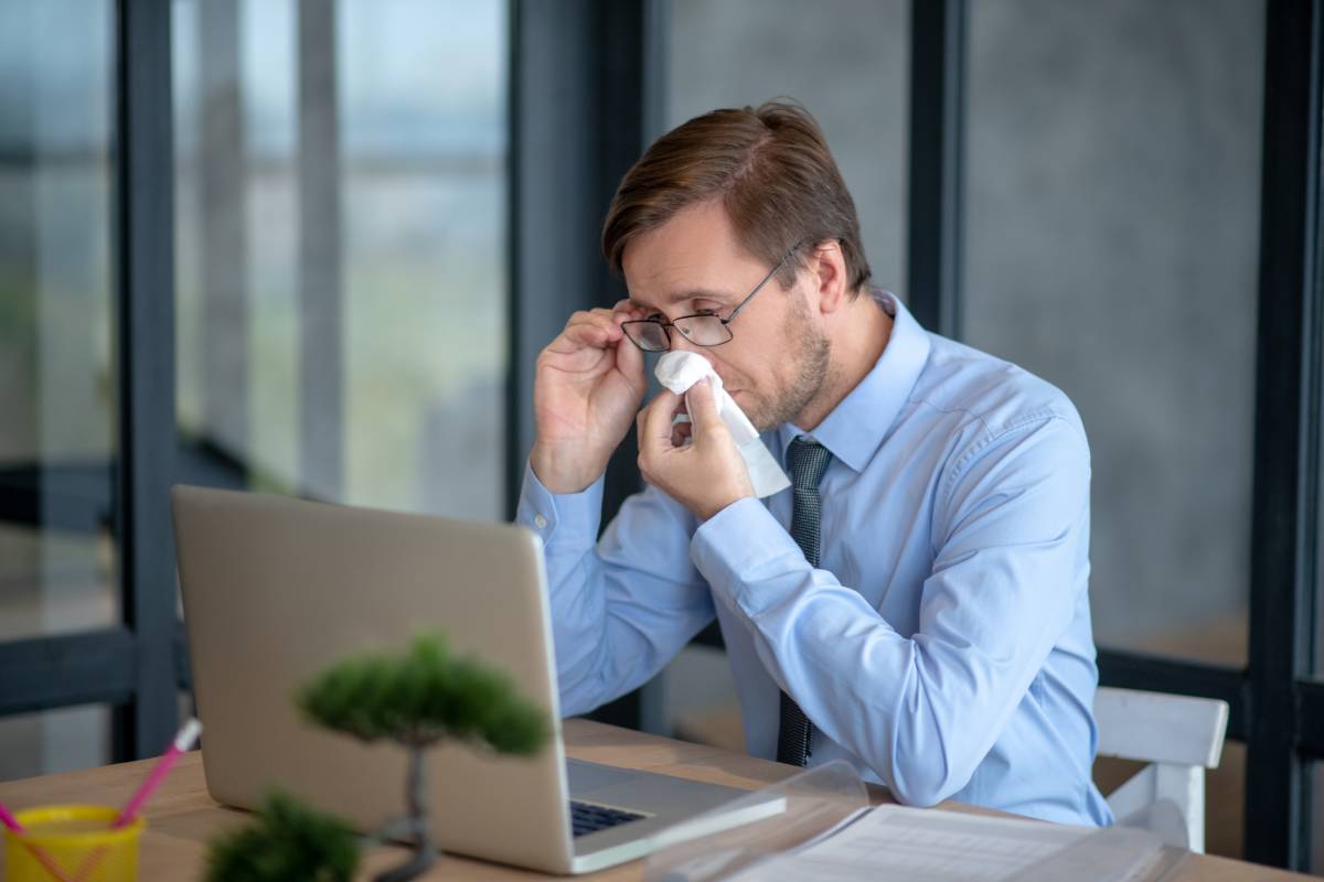 Dealing with allergy. Office worker holding napkin while dealing with seasonal allergy in the office